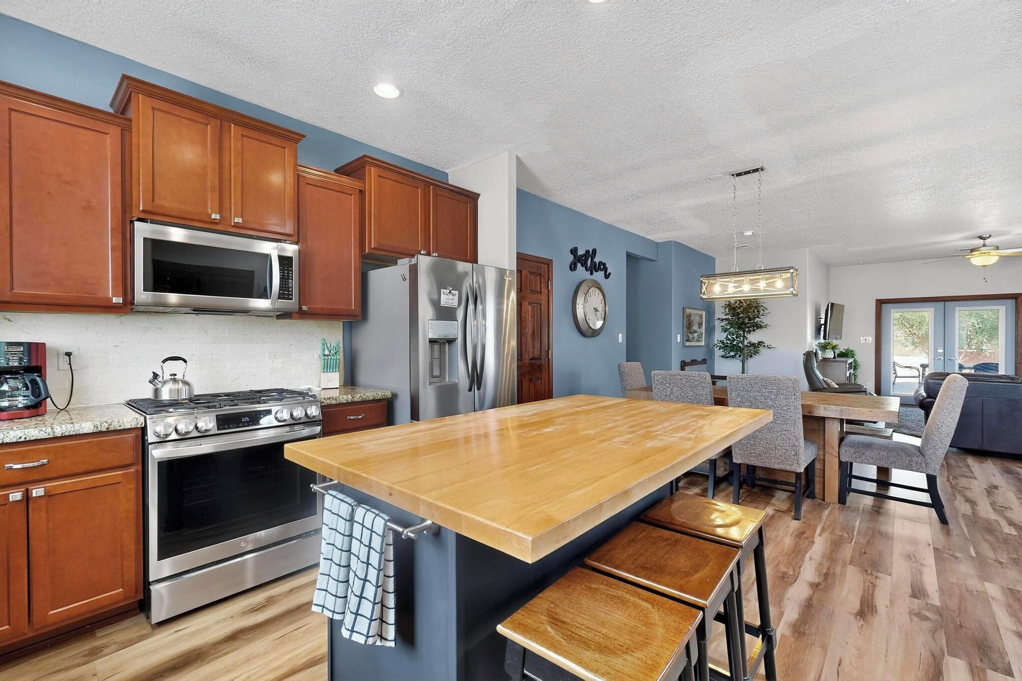 A modern kitchen with wooden cabinets, stainless steel appliances, and a central island with bar stools.