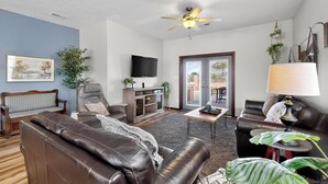 A living room with a brown leather sofa, a wooden coffee table, a TV, and a ceiling fan. - Beautiful North Valley home, garage, yard, BBQ (Albuquerque)