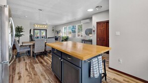 A modern kitchen with a wooden countertop, built-in appliances, and a dining area with a table and chairs. - Beautiful North Valley home, garage, yard, BBQ (Albuquerque)