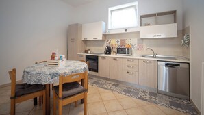 A compact kitchen with a dining table, chairs, a microwave, a coffee maker, and a dishwasher. - PORTA SUGLI ULIVI (Monopoli)