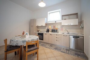 A compact kitchen with a dining table, chairs, a microwave, a sink, and a dishwasher.
