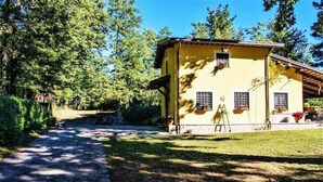 A yellow building with a paved driveway leading to it, surrounded by trees and greenery. - Villa Woodland Garden - Irpinia (Montemarano)