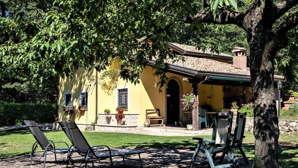 A yellow building with a patio area, outdoor seating, and a tree providing shade. - Villa Woodland Garden - Irpinia (Montemarano)