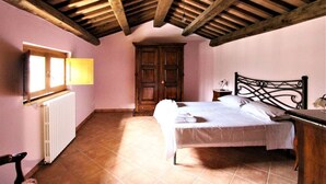 A bedroom with a bed, wooden ceiling beams, a radiator, and a wardrobe. - Villa Woodland Garden - Irpinia (Montemarano)