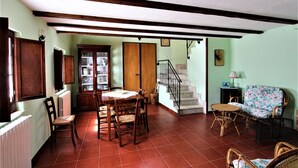 A dining area with a wooden table and chairs, a staircase, and a wicker sofa. - Villa Woodland Garden - Irpinia (Montemarano)