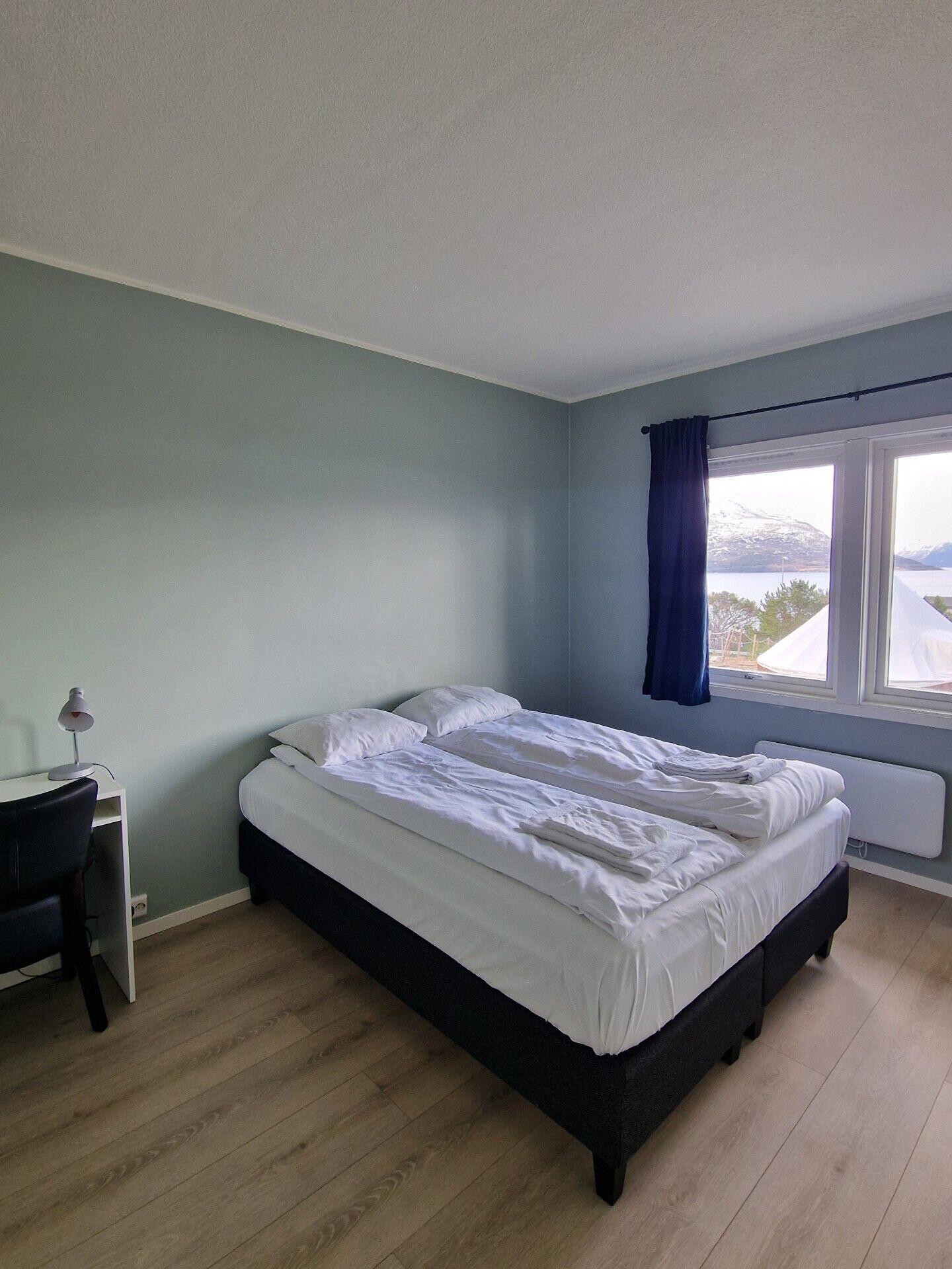 A bedroom with a bed, a desk, and a window with a view.