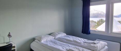 A bedroom with a bed, a desk, and a window with a view.