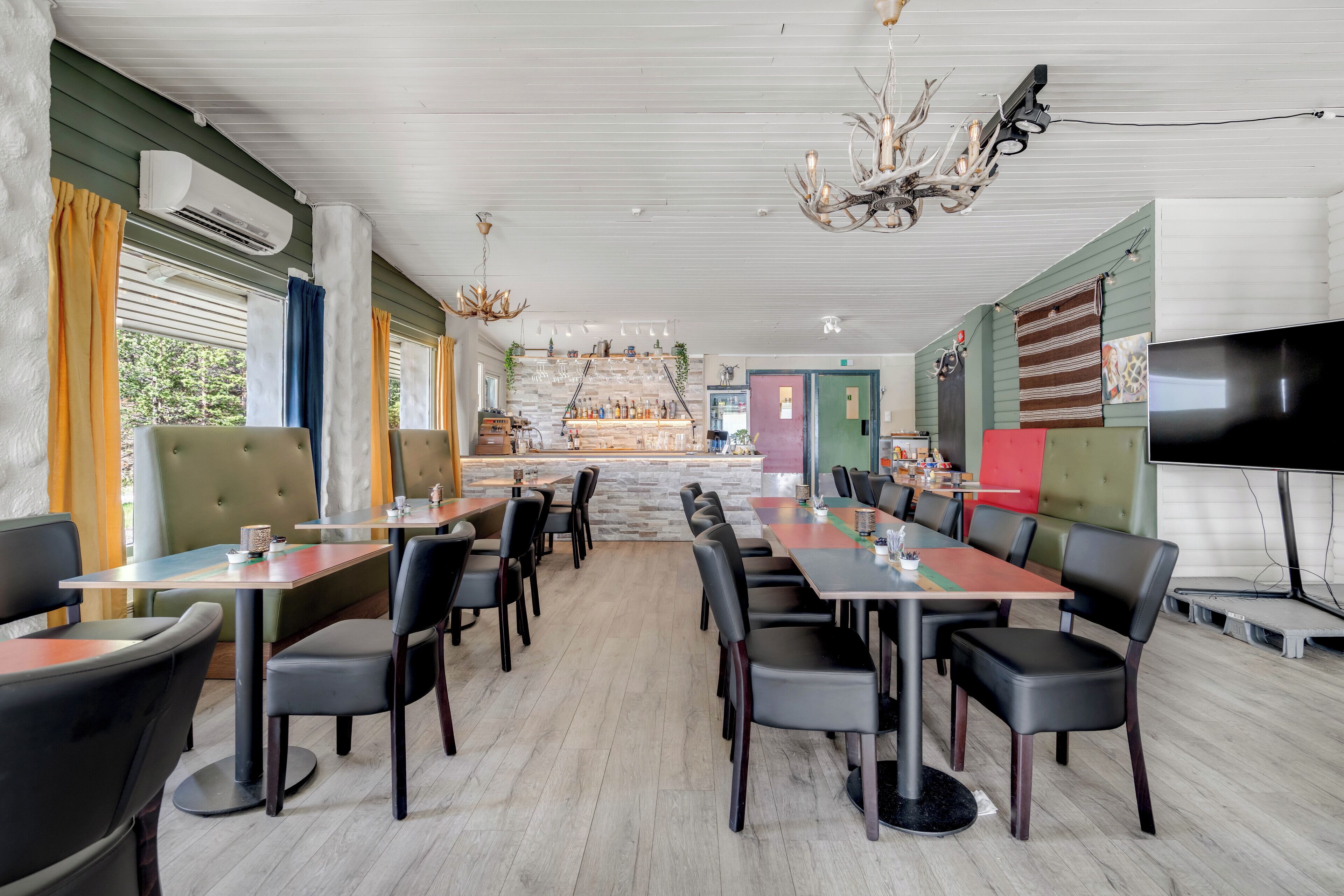 Un restaurant avec un long comptoir, des banquettes et un écran de télévision.