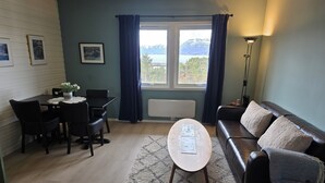 Ein Wohnzimmer mit Essbereich, einer Couch, einem Couchtisch und Blick ins Freie.