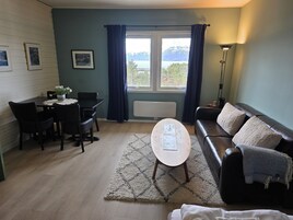 Una sala de estar con comedor, un sofá, una mesa de centro y vistas al exterior.