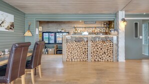 Eine Barbereich mit Holzbalkendecke, einer Theke und einem Holzstoß.