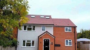 A two-story residential building with a brick facade, a tiled roof, and a front door with a small porch. - The Modern muse (Birmingham)