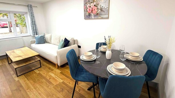 A dining area with a round table, blue chairs, and white plates. - The Modern muse (Birmingham)