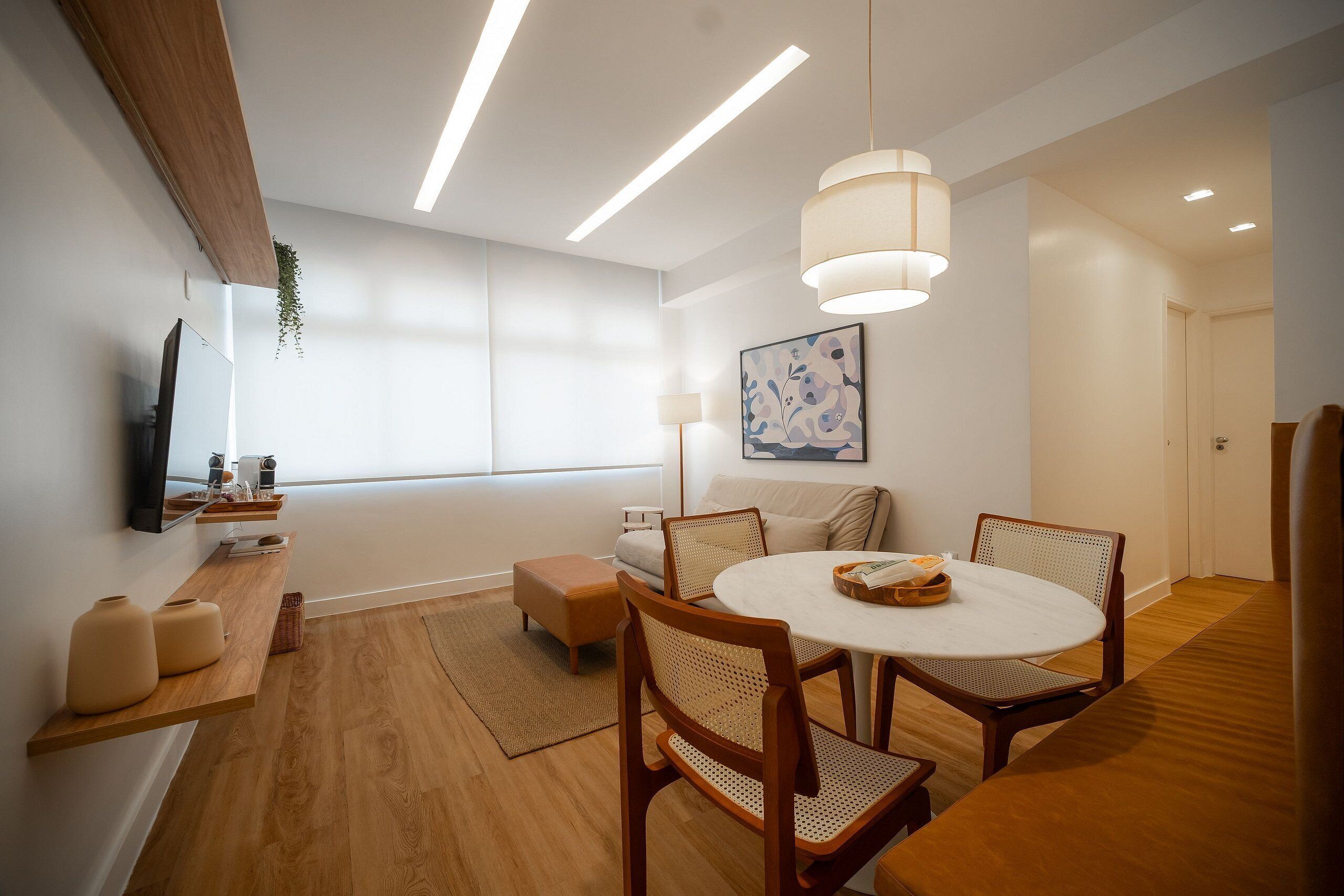 Un espace de salle à manger moderne avec une table ronde, des chaises en bois et des luminaires suspendus.