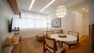 Un espace de salle à manger moderne avec une table ronde, des chaises en bois et des luminaires suspendus.