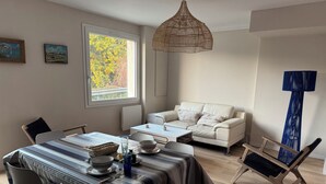 A dining area with a table set for two, a sofa, and a blue chair. - RENTAL HOUSE 2 BEDROOMS IN THE CENTER OF PORNIC FOR 4 PEOPLE (Pornic)