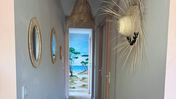 A hallway with a beach mural, two oval mirrors, and a straw art piece. - RENTAL HOUSE 2 BEDROOMS IN THE CENTER OF PORNIC FOR 4 PEOPLE (Pornic)