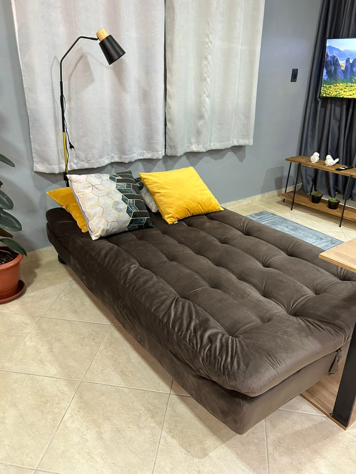 Un dormitorio moderno con una cama grande, una mesita de noche, una lámpara y un televisor en la pared.