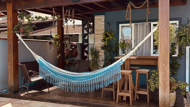 A poolside area with a hammock, wooden chairs, and a bar.