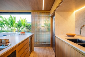 Uma cozinha moderna com bancada de madeira, pia de aço inoxidável e um painel decorativo de madeira.