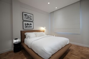 A modern bedroom with a wooden bed, a nightstand, and two framed abstract artworks on the wall. - Leblon | Recém reformado, 2 quartos, 5 min da Praia – por Casapē Rio (Rio de Janeiro)