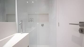 Een moderne badkamer met een wit wastafelmeubel, een douchecabine van glas en een spiegel.