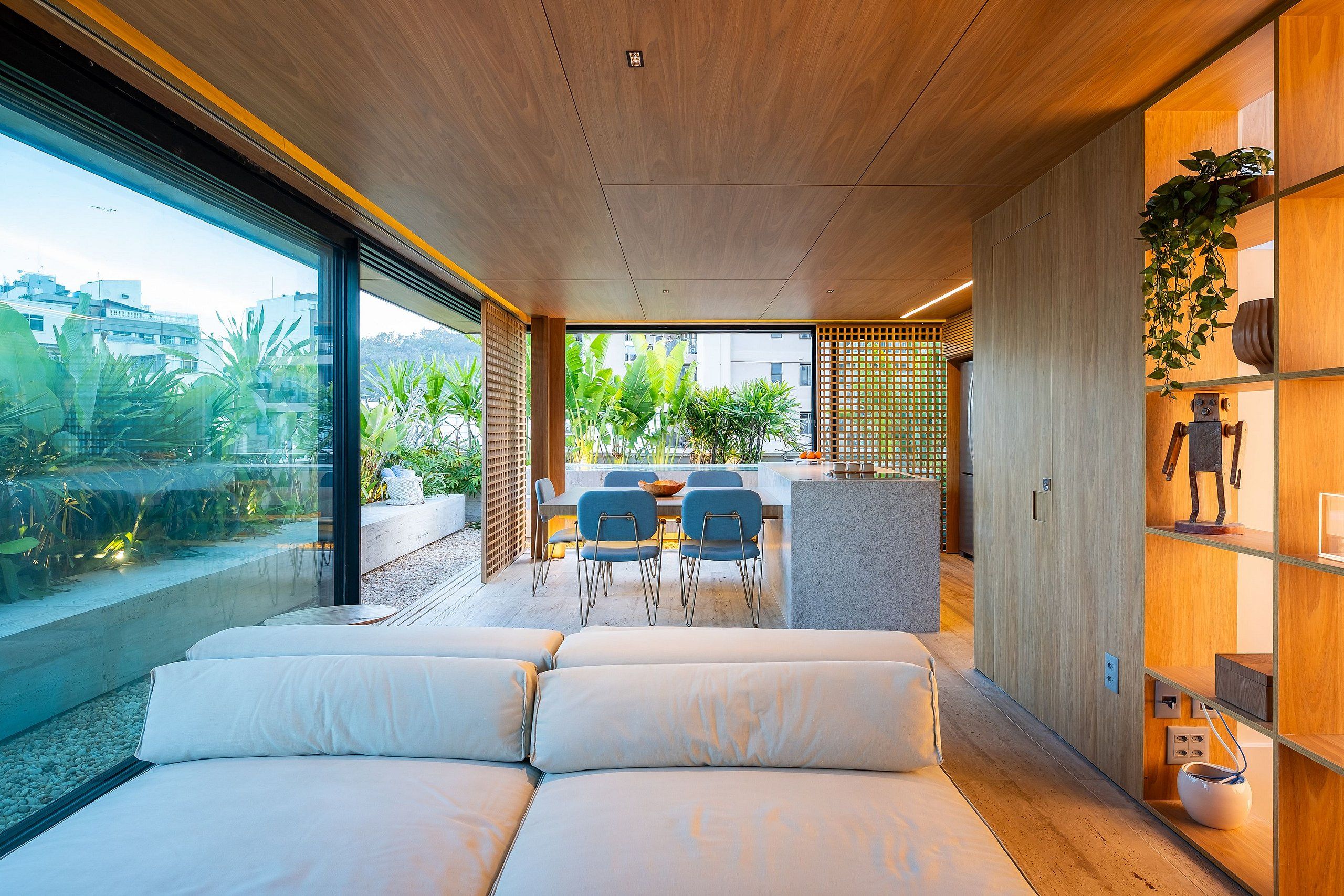 Un interior moderno con sofá, comedor y vistas al exterior con vegetación.