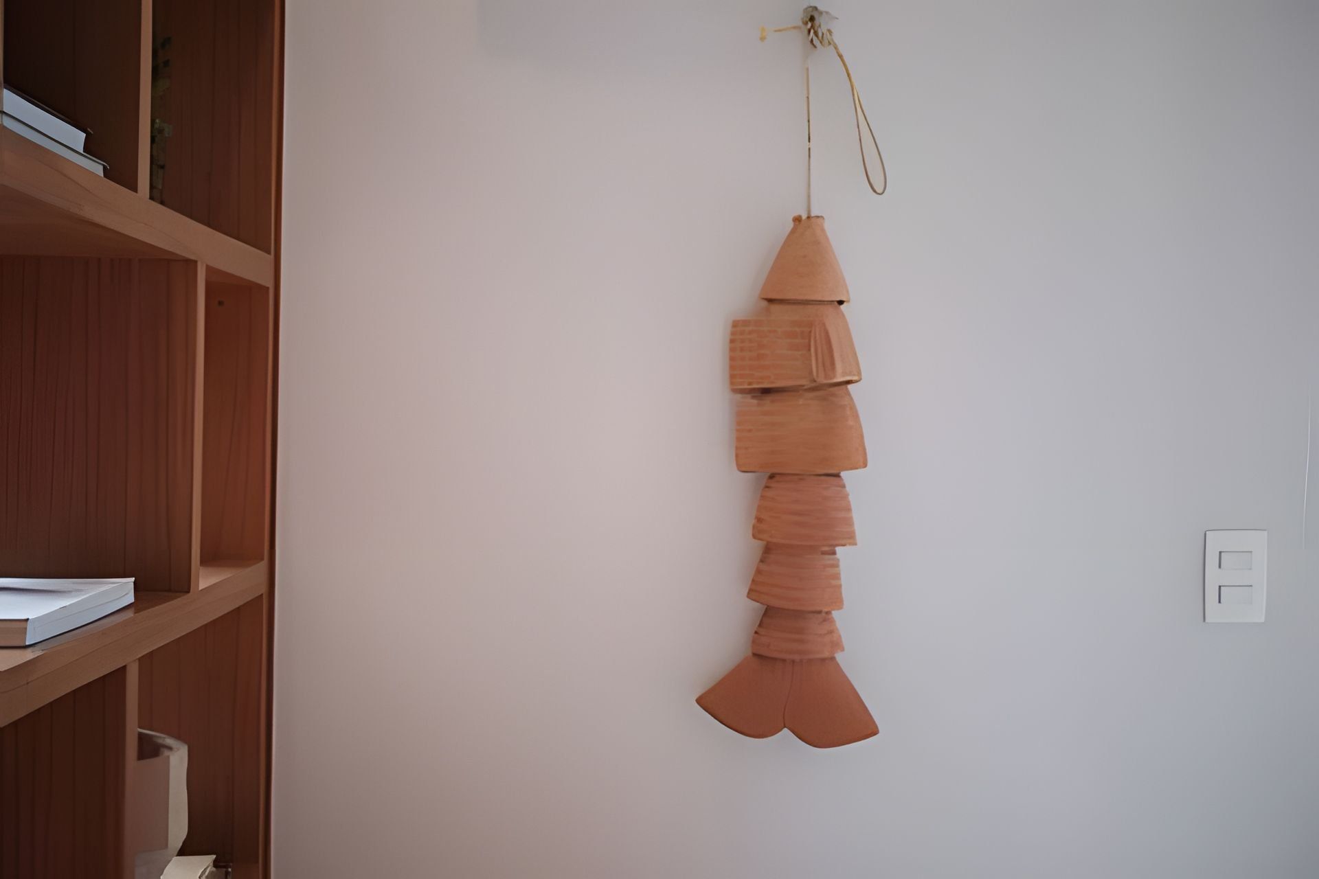 Habitació amb una prestatgeria de fusta i un objecte decoratiu penjant.