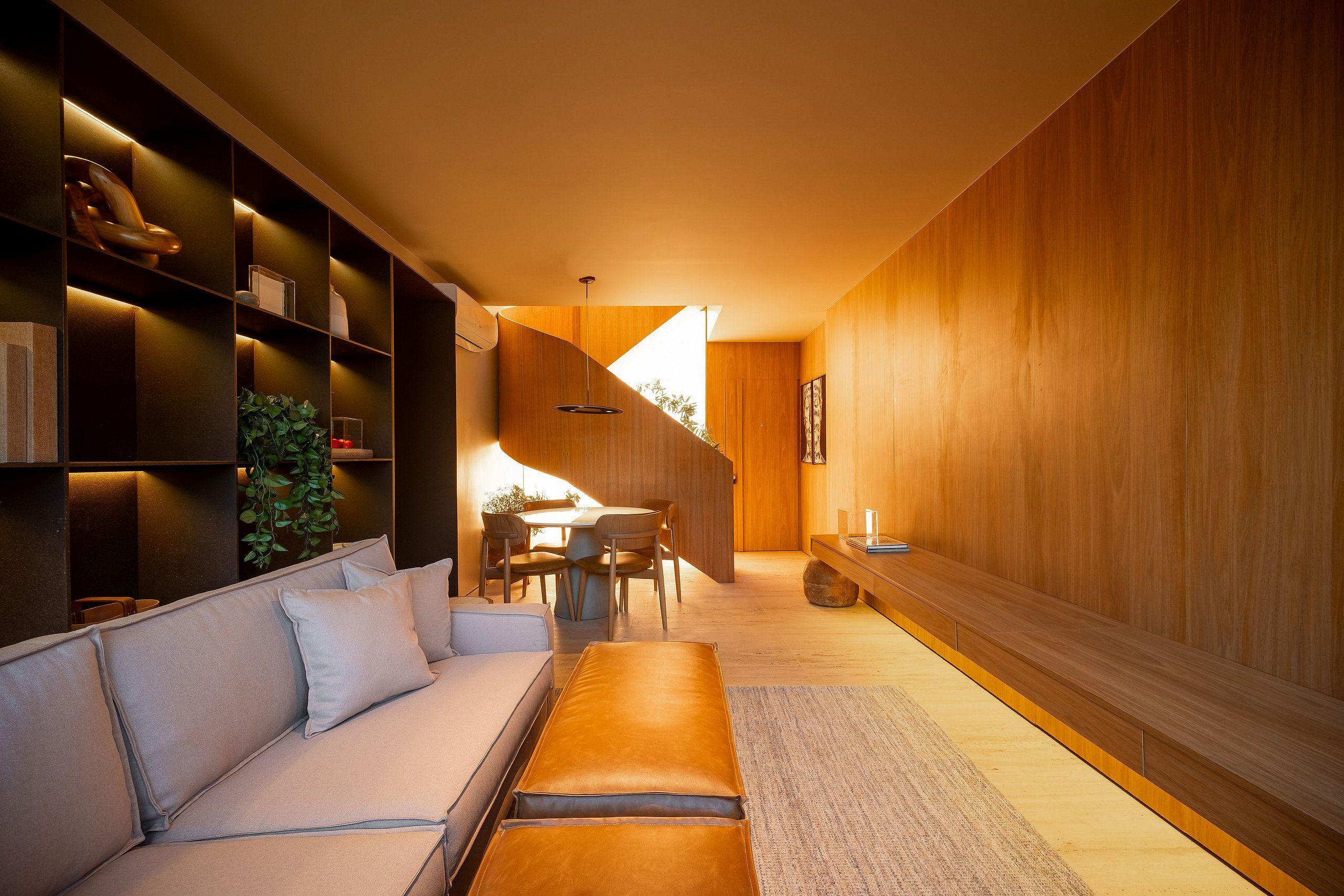 Een modern interieur met een bank, eettafel en houten lambrisering.