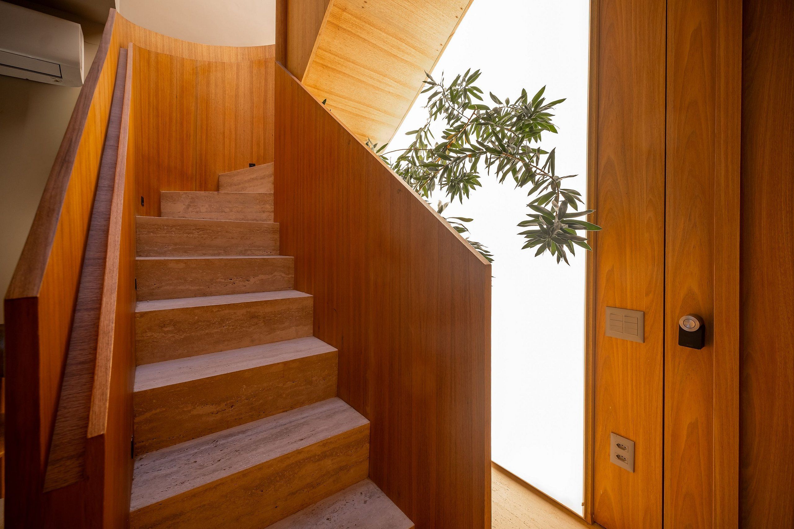 A wooden staircase leading to a room with a door and a power outlet.