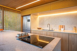 A modern kitchen with a built-in stove, a refrigerator, and a sink. - Leblon | Recém reformado, 2 quartos, 5 min da Praia – por Casapē Rio (Rio de Janeiro)