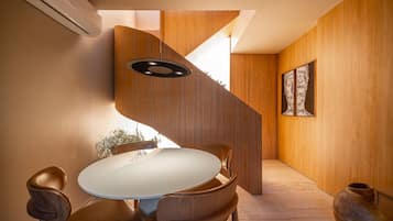 Een modern interieur met een ronde eettafel, houten stoelen, een wenteltrap en een grote vaas.