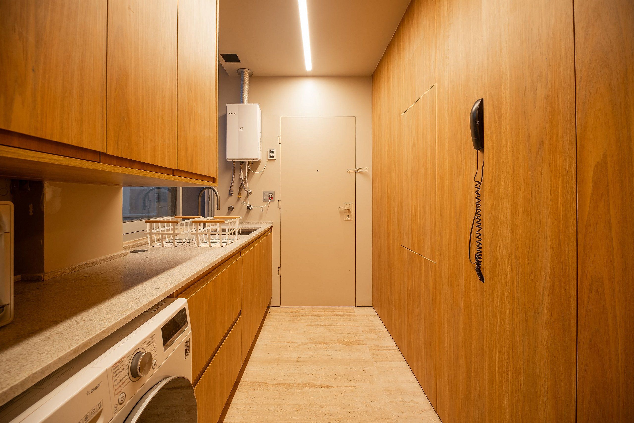 A compact kitchen with wooden cabinets, a built-in washing machine, and a water heater.