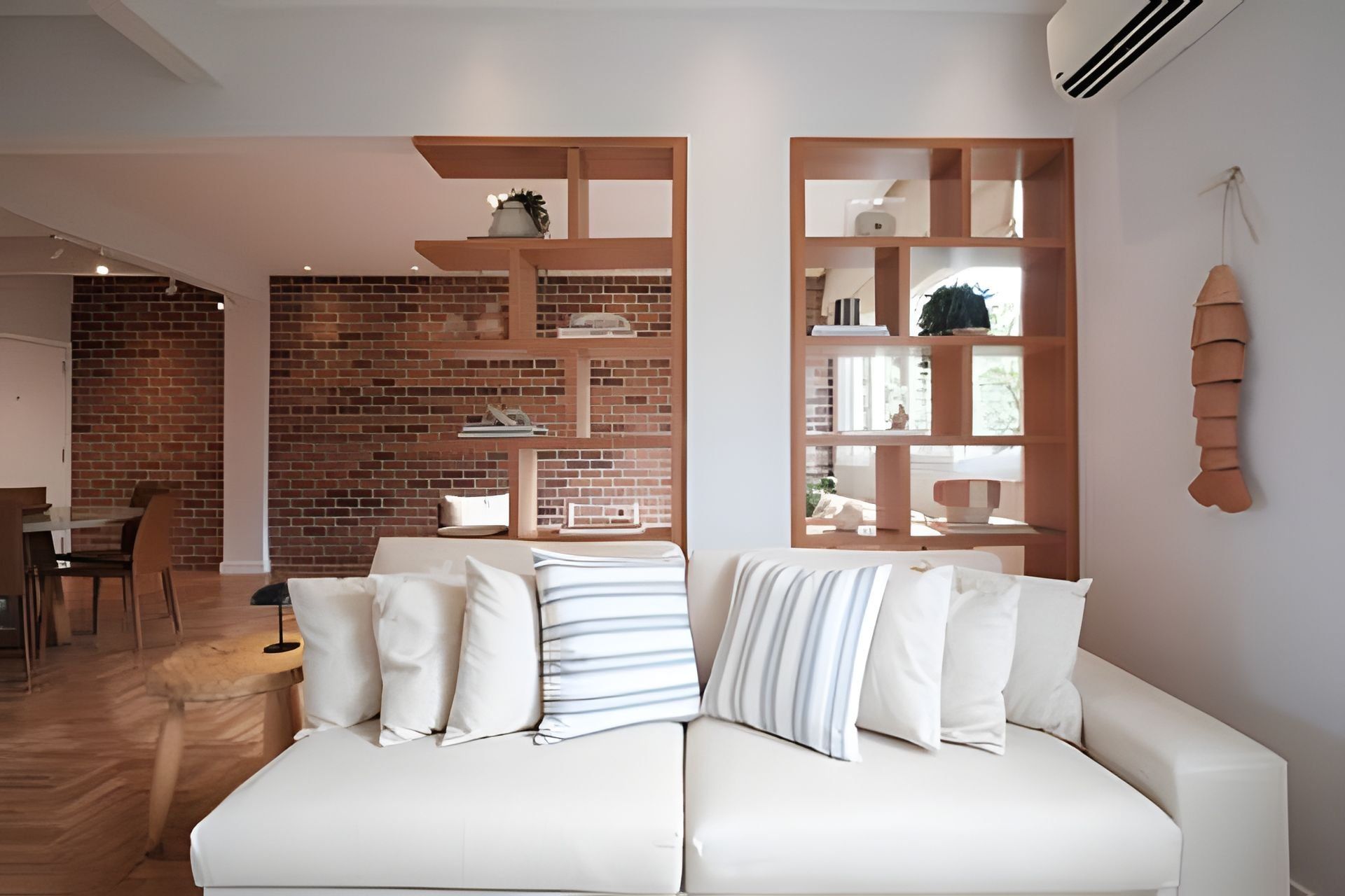 Un salon moderne avec un canapé blanc, des étagères en bois et un mur en briques.