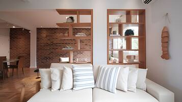 Un salon moderne avec un canapé blanc, des étagères en bois et un mur en briques.
