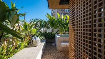 Un jardin aménagé sur le toit, avec une variété de plantes tropicales, un bac à plantes en béton et une clôture en treillis de bois.