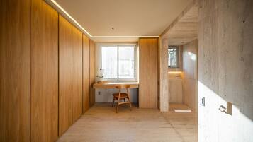 A modern interior with a wooden wardrobe, a desk with a chair, and a large window.