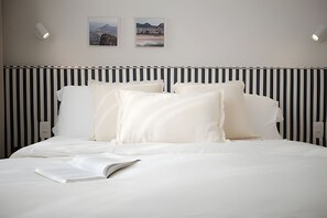 A hotel room with a bed, white bedding, a striped headboard, and two framed pictures on the wall. - Leblon | Recém reformado, 2 quartos, 5 min da Praia – por Casapē Rio (Rio de Janeiro)