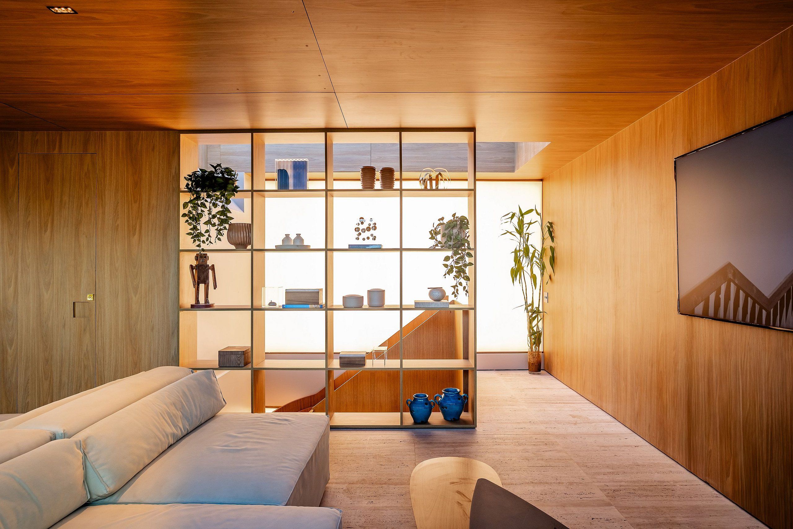 Een modern interieur met een houten vloer, een bank, een boekenkast en een trap.