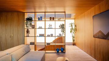 Een modern interieur met een houten vloer, een bank, een boekenkast en een trap.