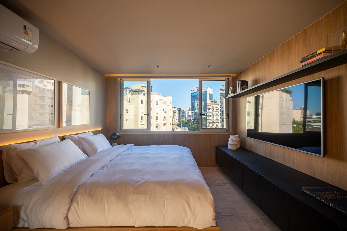 Habitación de hotel con una cama grande, televisión y vistas de la ciudad.