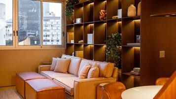 Uma sala de estar moderna com sofá, apoio para os pés e um espaço de jantar com mesa.