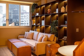 Uma sala de estar moderna com sofá, apoio para os pés e um espaço de jantar com mesa.