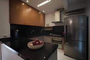 Una cocina moderna con encimera negra, electrodomésticos de acero inoxidable y armarios de madera.