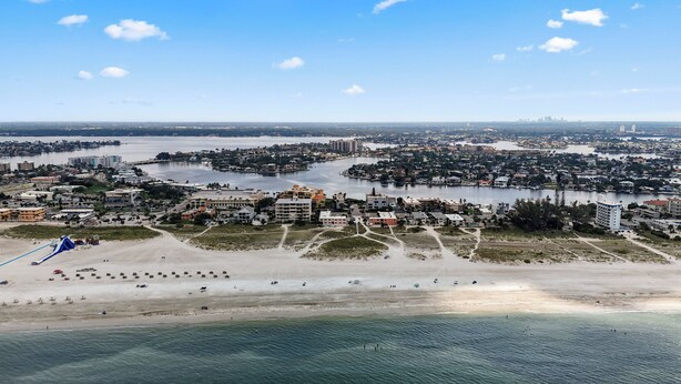 Ein Luftbild einer Küstenstadt mit Strand, Gebäuden und einem Fluss.