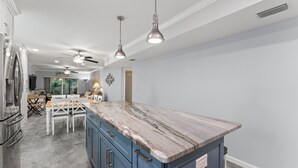 Eine moderne Küche mit Marmorarbeitsplatte, blauen Schränken und einem Deckenventilator.