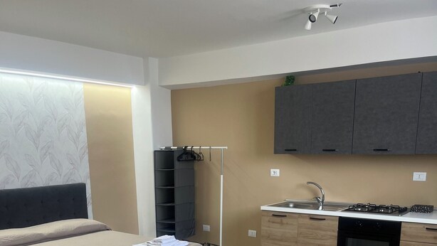 A modern hotel room with a bed, bedside table, and a small kitchenette. - Aunt Lisa home (Catania)