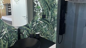 A modern bathroom with a round black sink, a mirror, and a shower area. - Aunt Lisa home (Catania)