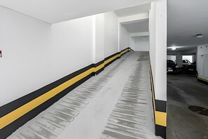 A parking garage with a concrete ramp leading to a garage door. - Rua Dias Ferreira, 646 - Tesouro Escondido no Leblon (Rio de Janeiro)