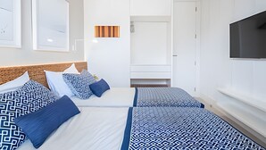Una camera d'albergo con due letti, una televisione e un'ampia finestra.